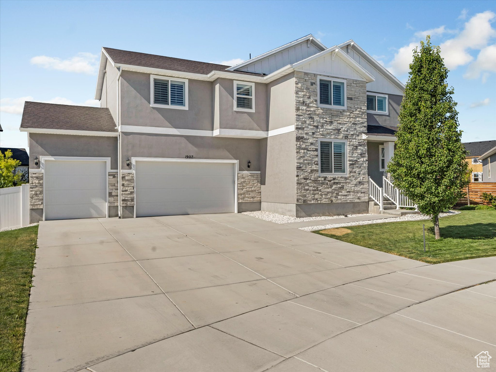 View of front of property featuring stone siding, driveway, and stucco siding