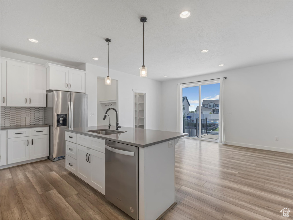 Kitchen with stainless steel appliances, recessed lighting, backsplash, light wood finished floors, and white cabinetry