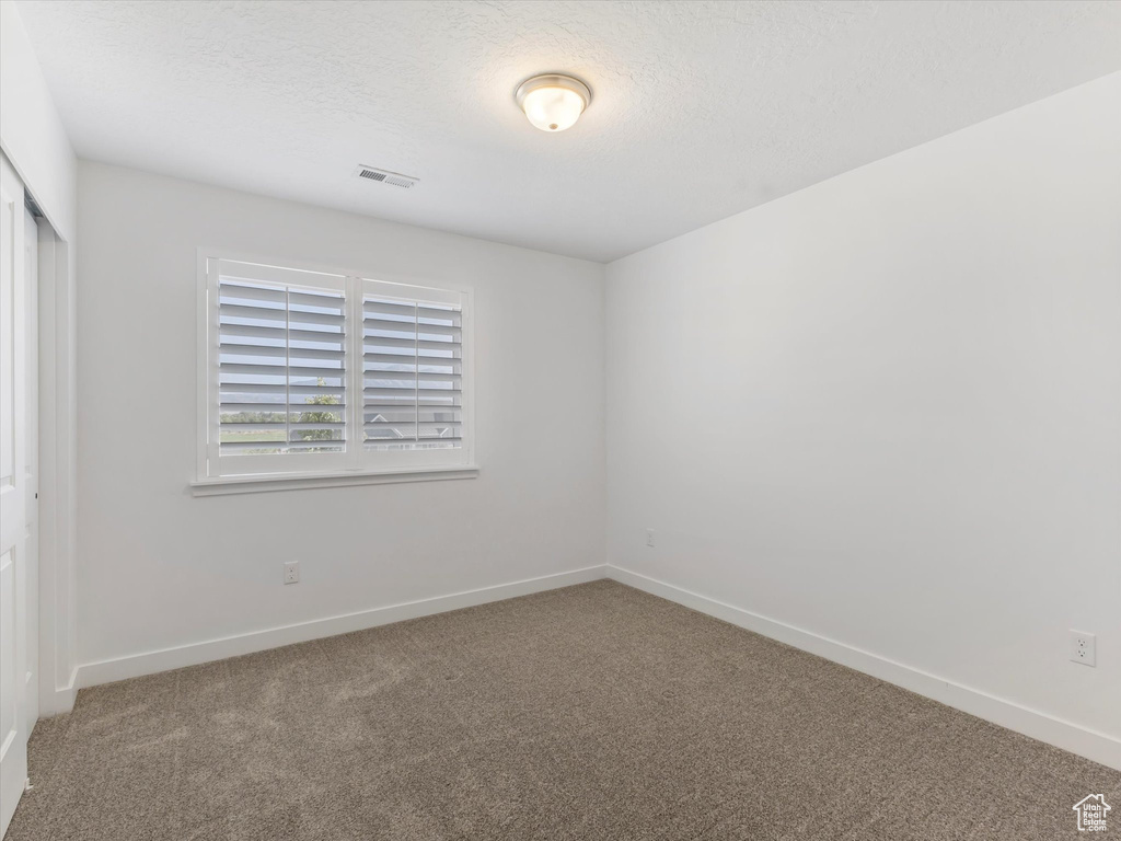 Carpeted empty room with a textured ceiling