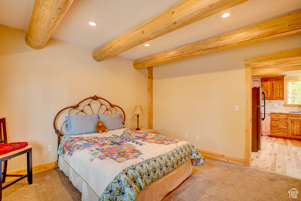 Bedroom featuring freestanding refrigerator, recessed lighting, beamed ceiling, and light colored carpet