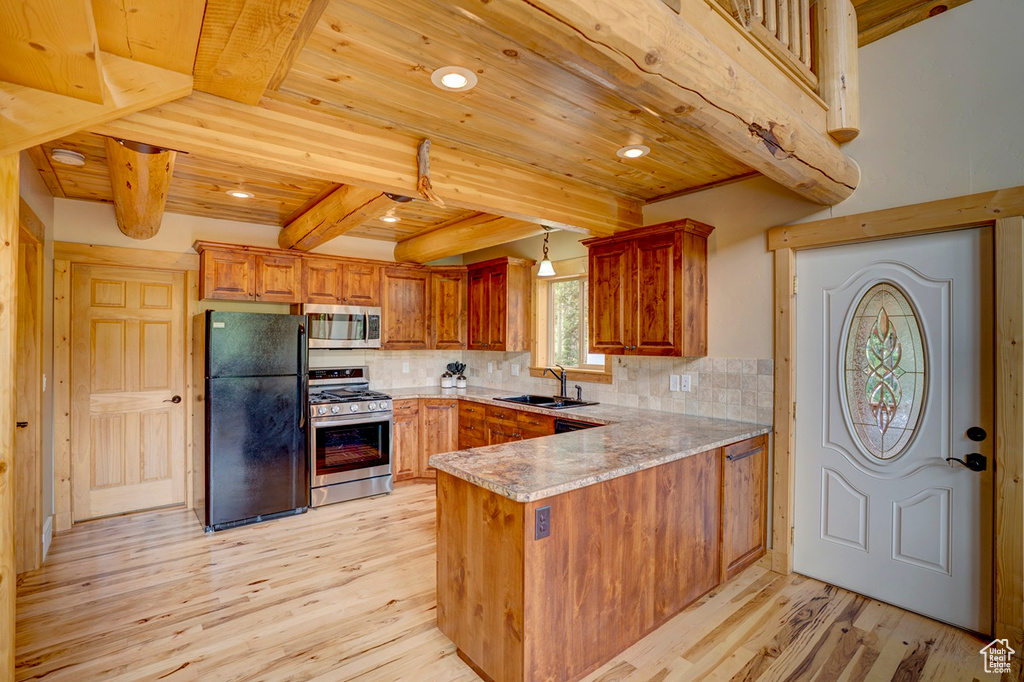Kitchen with appliances with stainless steel finishes, a wood ceiling with exposed beams, light wood-style floors, a peninsula, and tasteful backsplash