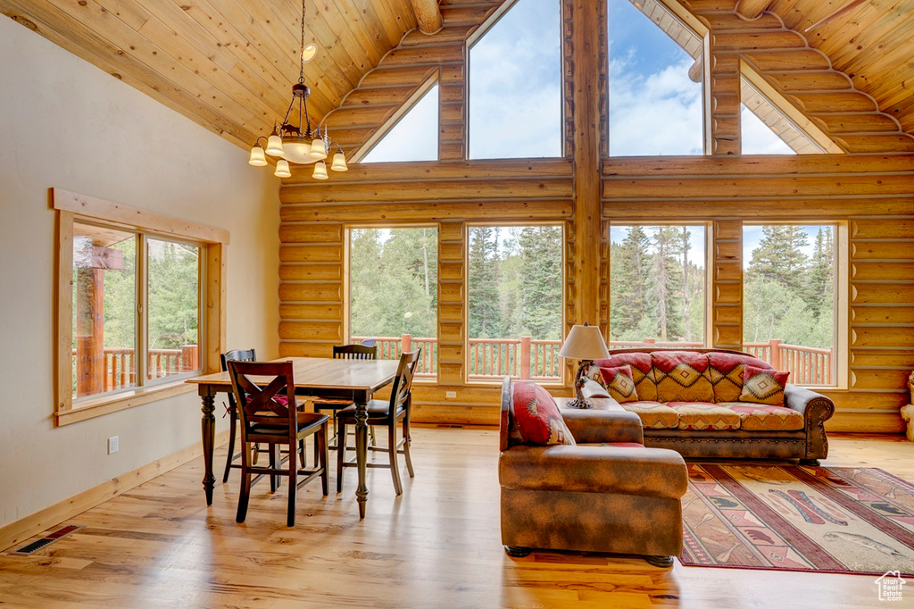 Dining area with high vaulted ceiling, log walls, wood ceiling, a chandelier, and light wood finished floors