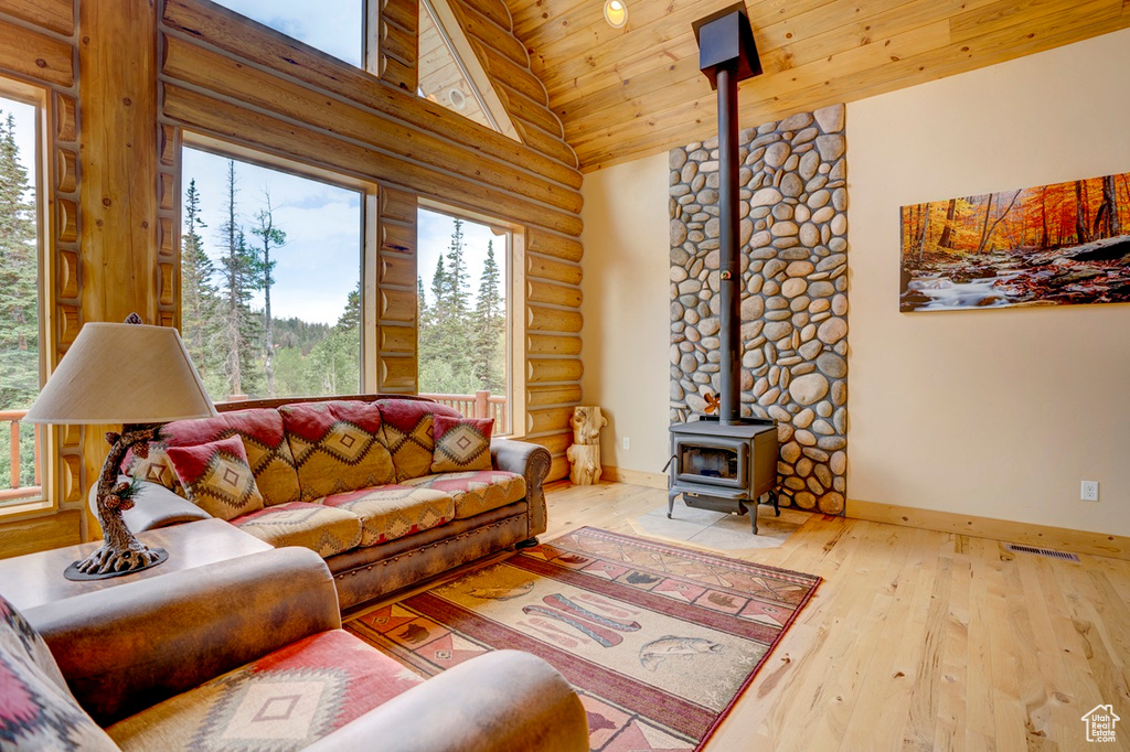 Living area featuring a wood stove, log walls, high vaulted ceiling, hardwood / wood-style floors, and wood ceiling