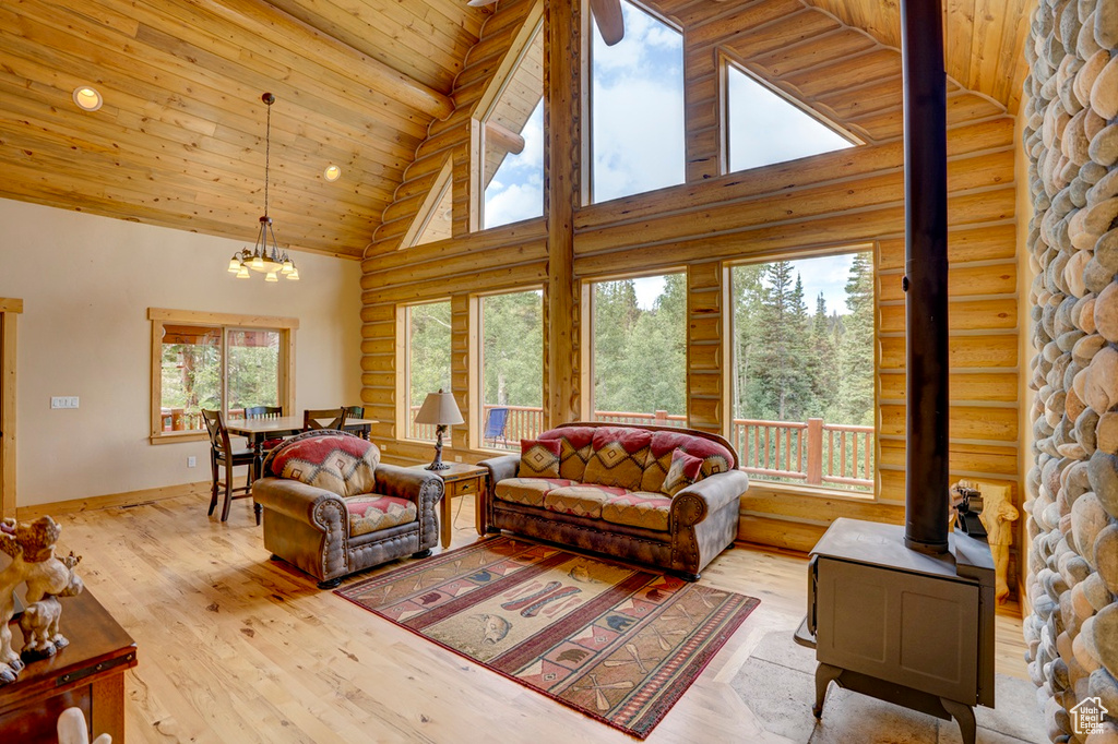 Living area featuring high vaulted ceiling, wooden ceiling, a wood stove, wood finished floors, and a chandelier