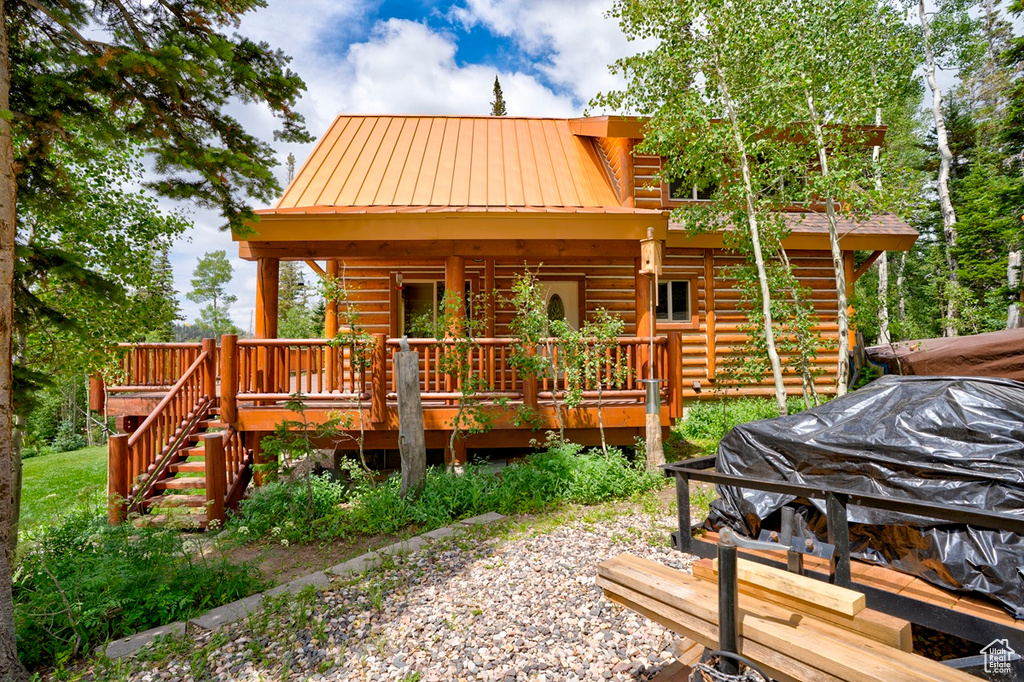 Rear view of property featuring a metal roof, log siding, and a deck
