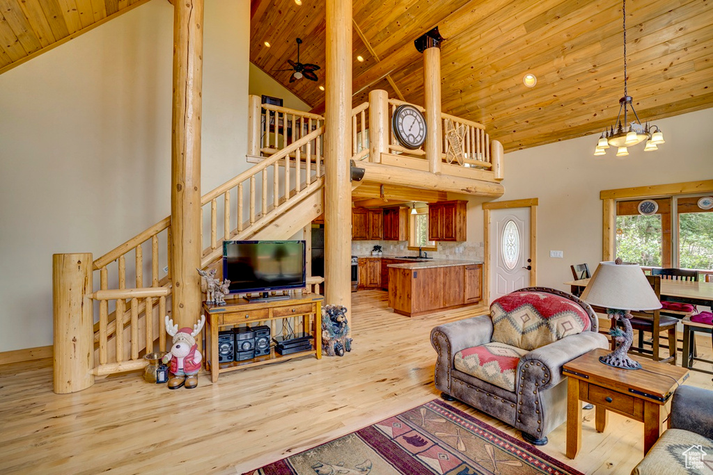 Living area with wooden ceiling, high vaulted ceiling, stairway, light wood finished floors, and a chandelier