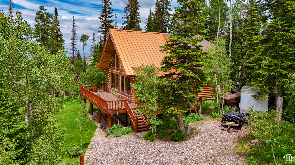 Rear view of house with log siding, a wooden deck, stairway, a metal roof, and a standing seam roof