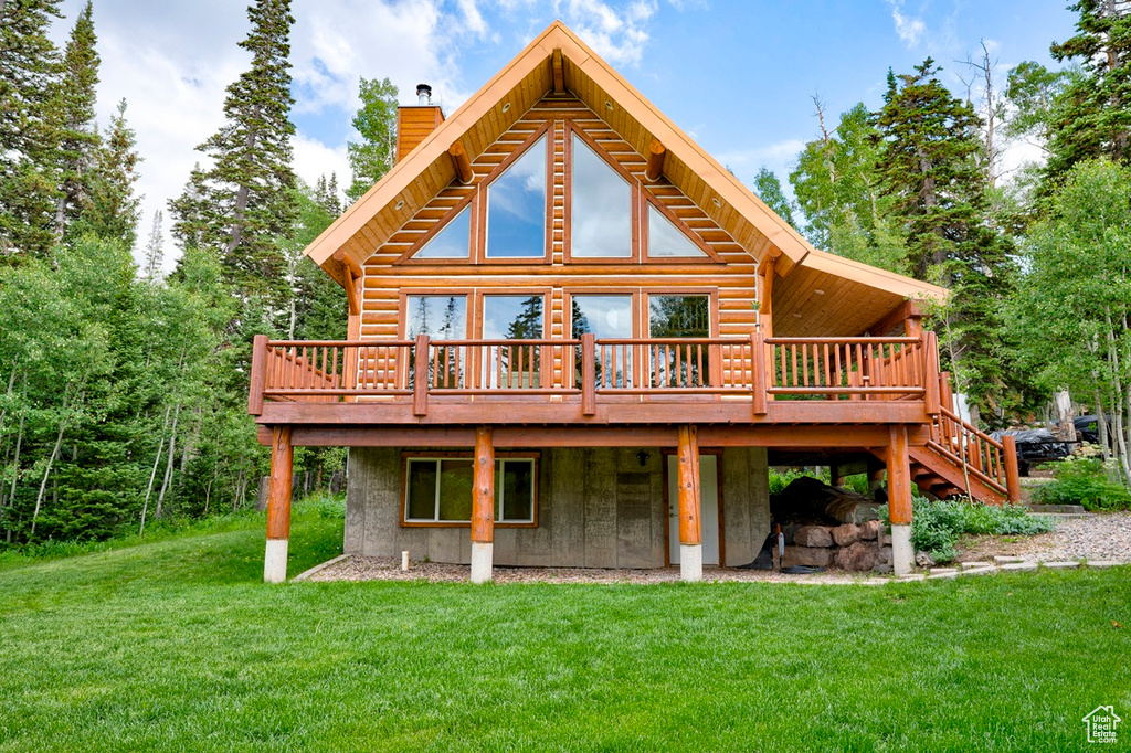 Rear view of house featuring a wooden deck, a chimney, and a yard