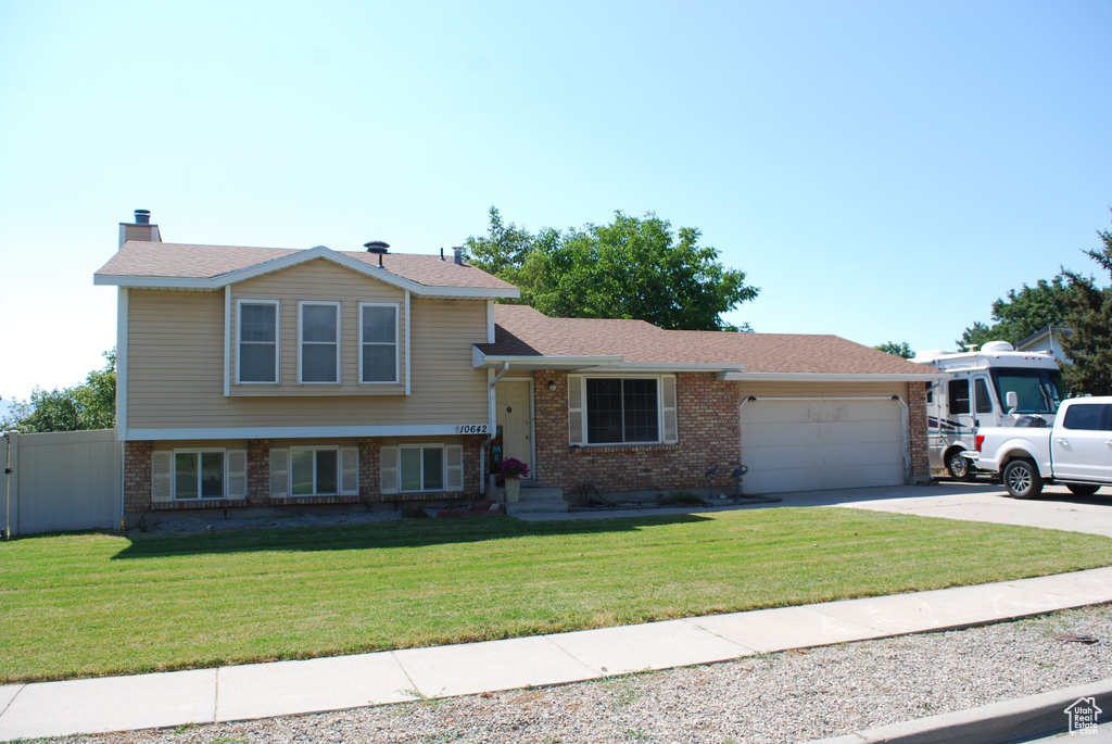 Tri-level home featuring brick siding, a garage, concrete driveway, and a shingled roof