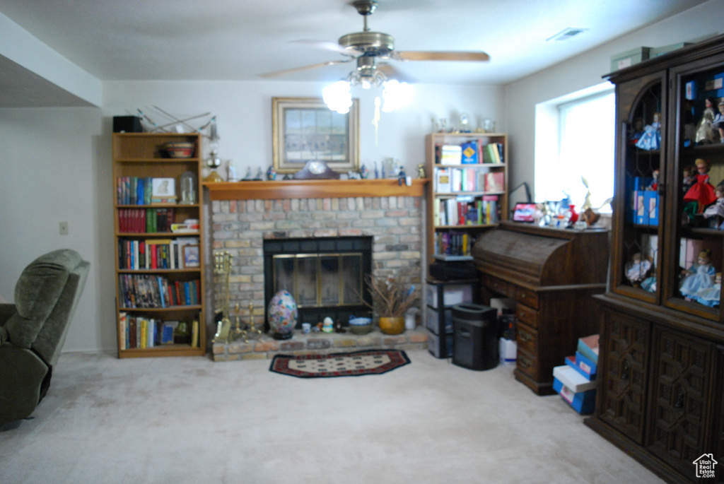 Living area with a ceiling fan, a fireplace, and carpet floors