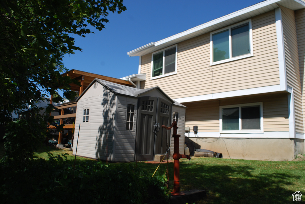 Back of property with a lawn and a storage shed