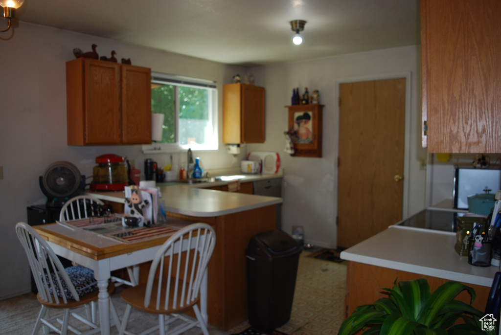 Kitchen with brown cabinetry, light countertops, and a peninsula