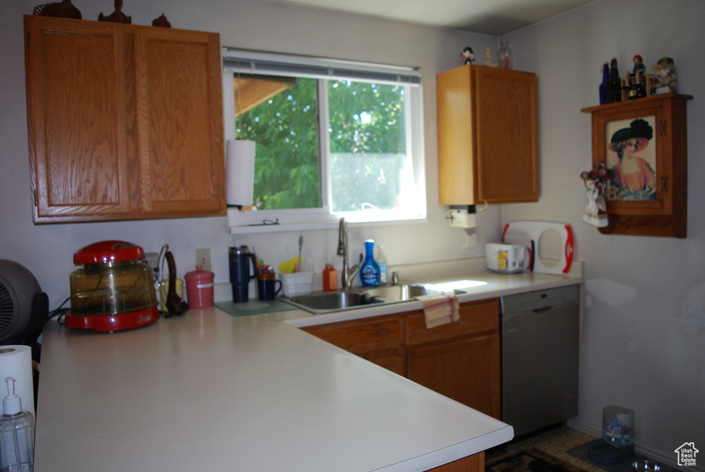 Kitchen featuring dishwasher, light countertops, and brown cabinetry