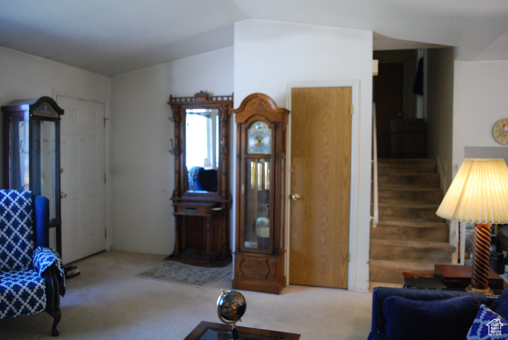 Living room featuring carpet flooring, lofted ceiling, and stairway