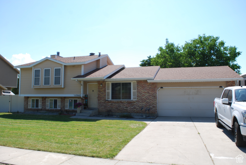 Tri-level home featuring brick siding, a garage, concrete driveway, and roof with shingles