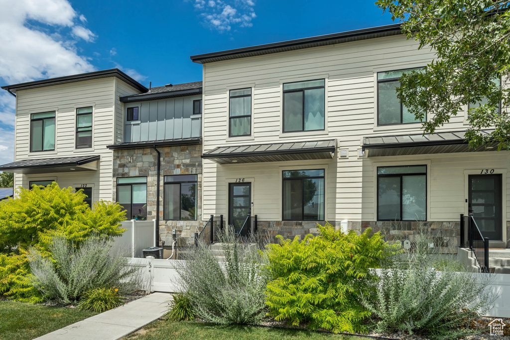 Back of property featuring stone siding, a standing seam roof, and a metal roof
