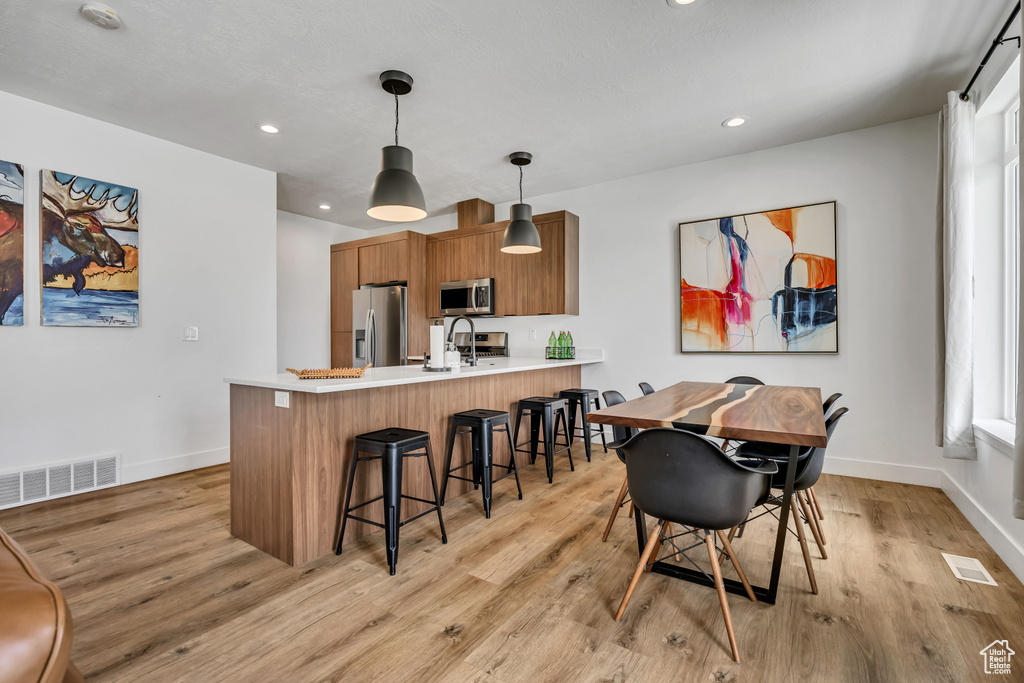 Dining area with light wood-style floors and recessed lighting