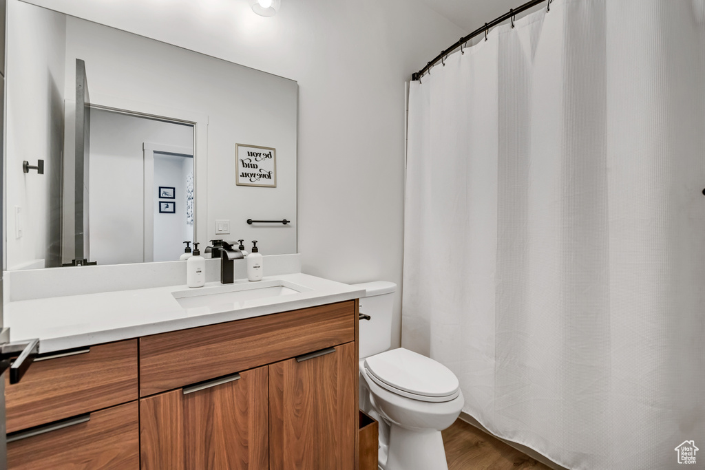 Full bathroom with vanity, curtained shower, and wood finished floors