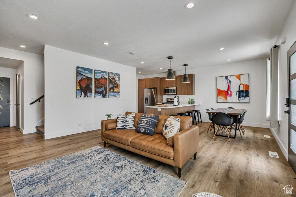 Living room featuring light wood finished floors, recessed lighting, and stairway