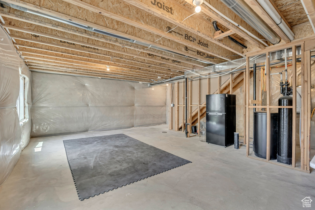 Below grade area with freestanding refrigerator and a water softener system