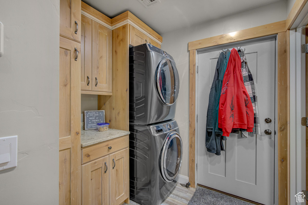 Laundry room with stacked washer / drying machine and cabinet space