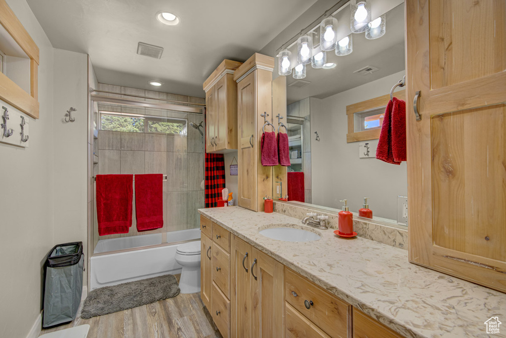 Full bathroom featuring vanity, wood finished floors, combined bath / shower with glass door, and recessed lighting