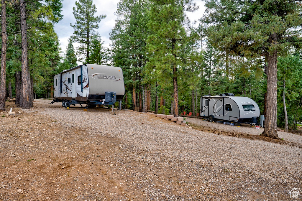 View of parking with view of wooded area and driveway