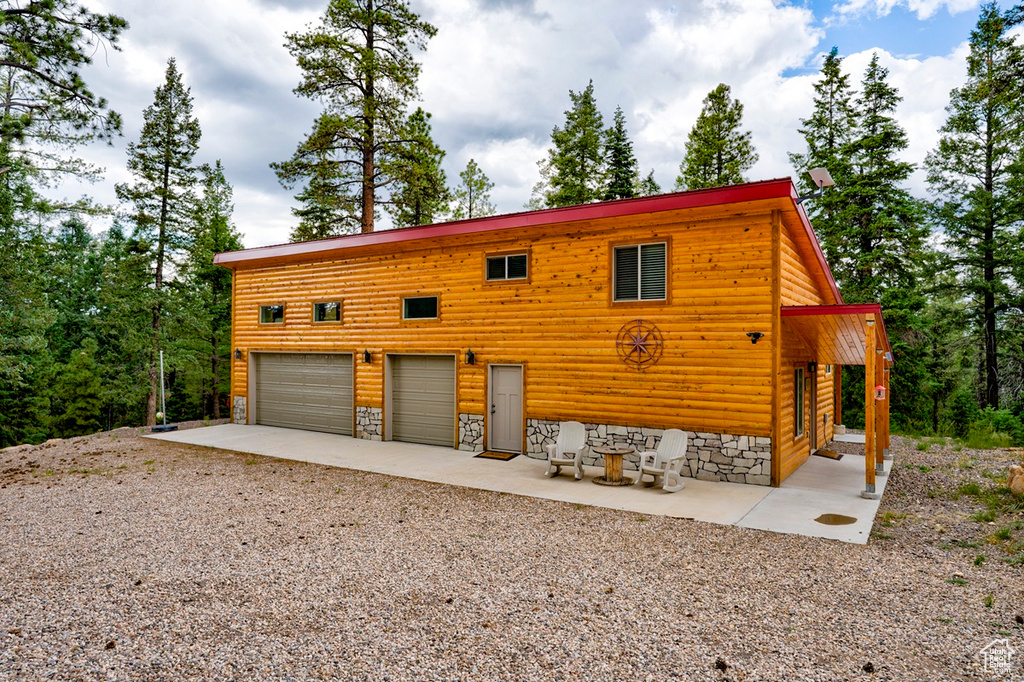 Chalet / cabin featuring driveway, an attached garage, and log veneer siding
