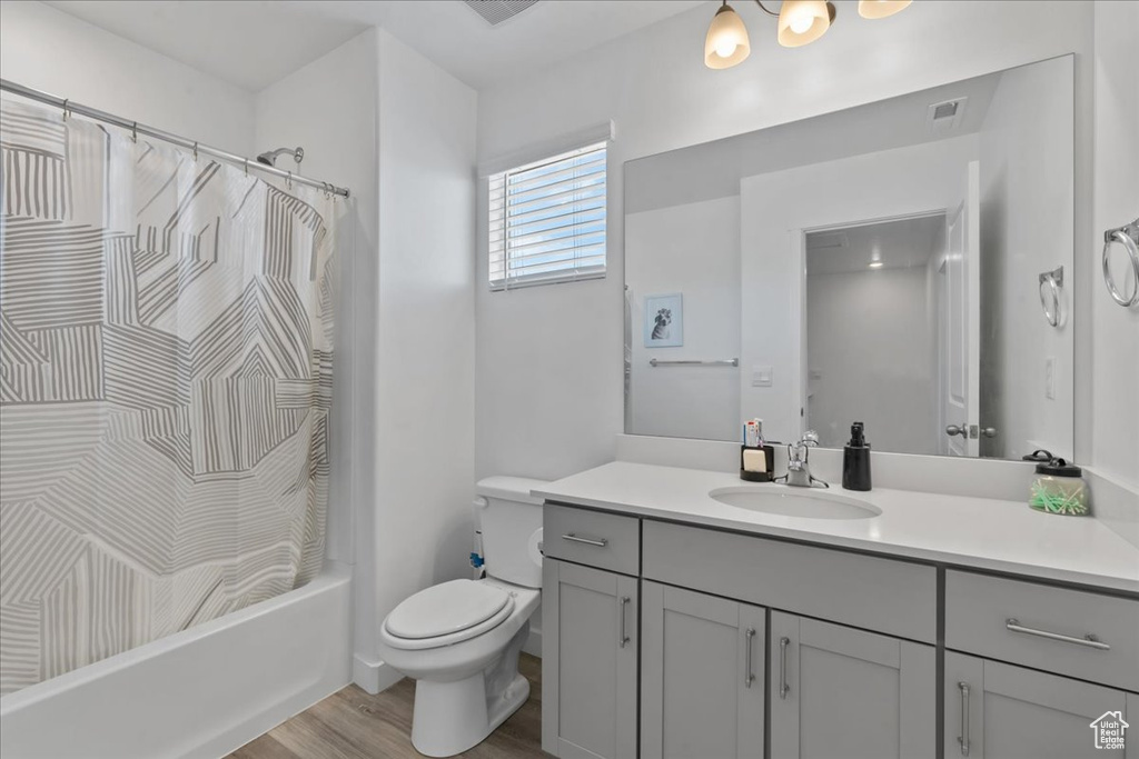 Full bath with vanity, wood finished floors, and shower / bath combo with shower curtain