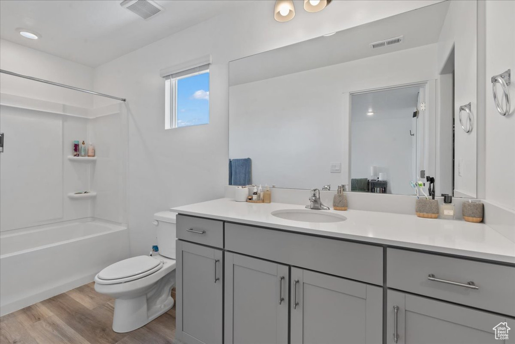 Bathroom featuring vanity, wood finished floors, and  shower combination