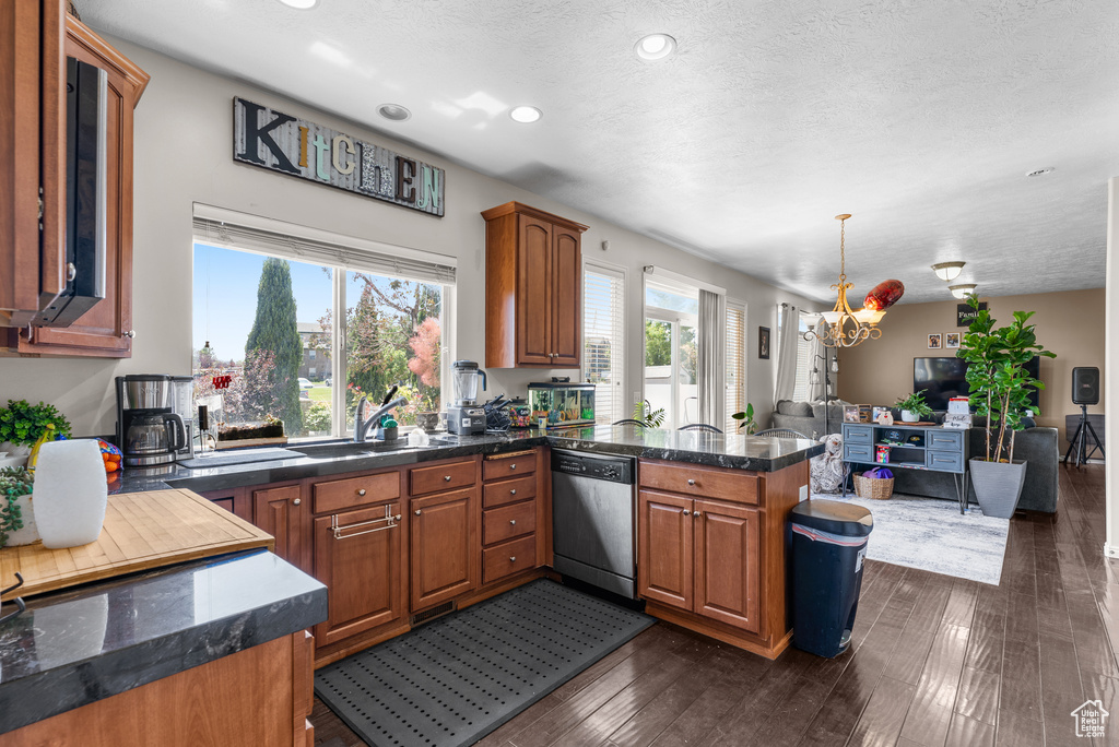 Kitchen featuring dishwasher, a chandelier, a peninsula, open floor plan, and dark countertops