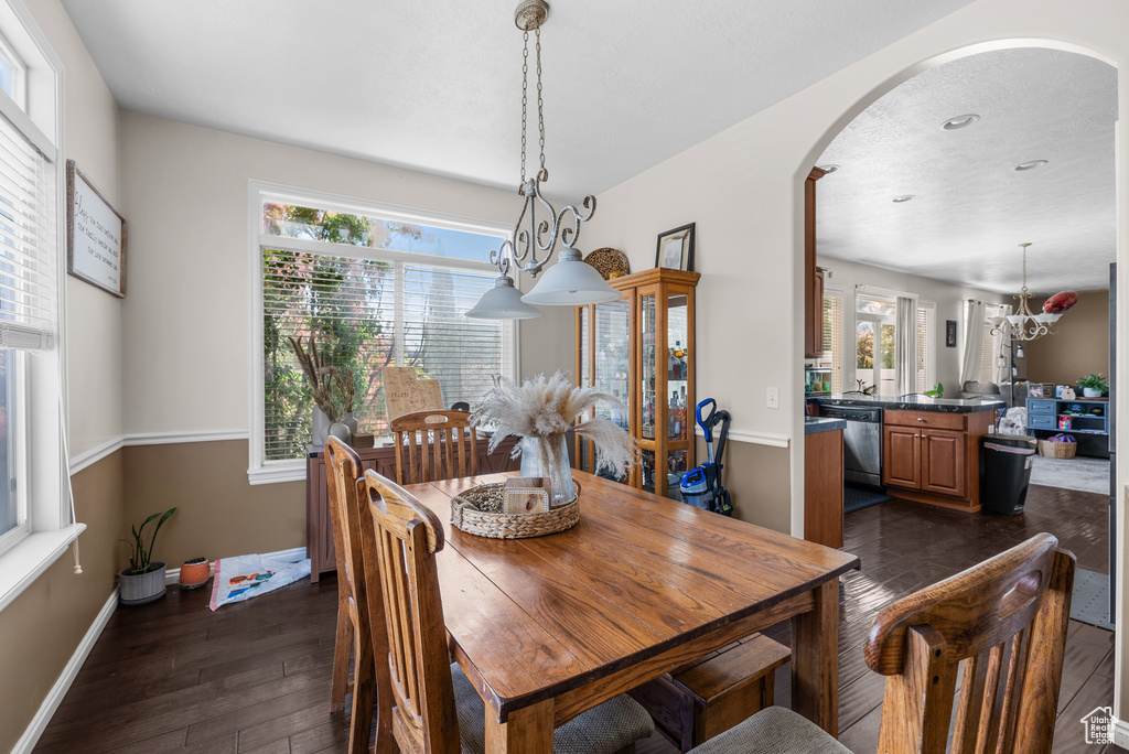 Dining room with arched walkways, dark wood-style flooring, recessed lighting, and a chandelier