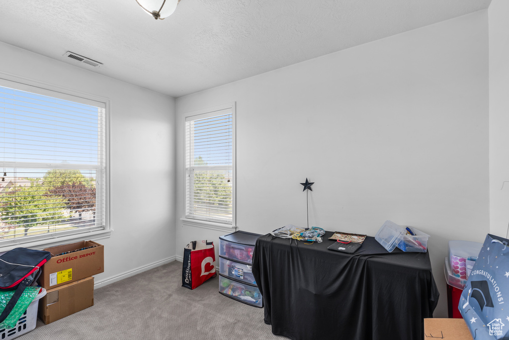 Carpeted office space featuring a textured ceiling and baseboards