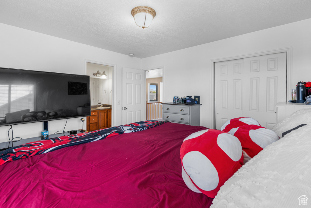 Bedroom featuring a closet, ensuite bath, and a textured ceiling