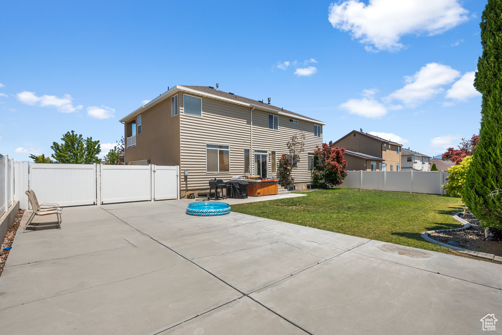 Rear view of house with a patio area, a hot tub, a fenced backyard, and a gate