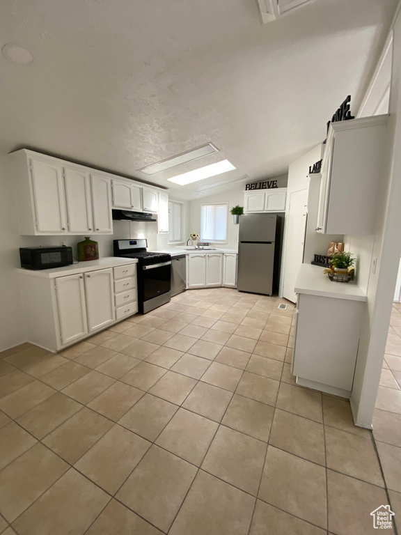 Kitchen featuring stainless steel appliances, light tile patterned floors, under cabinet range hood, light countertops, and white cabinetry