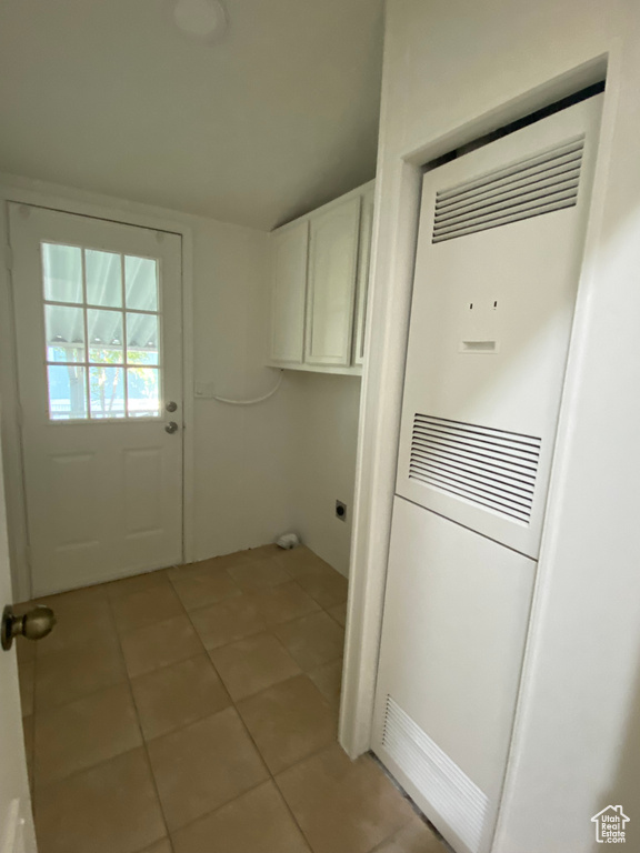 Laundry room with cabinet space, a heating unit, and light tile patterned floors
