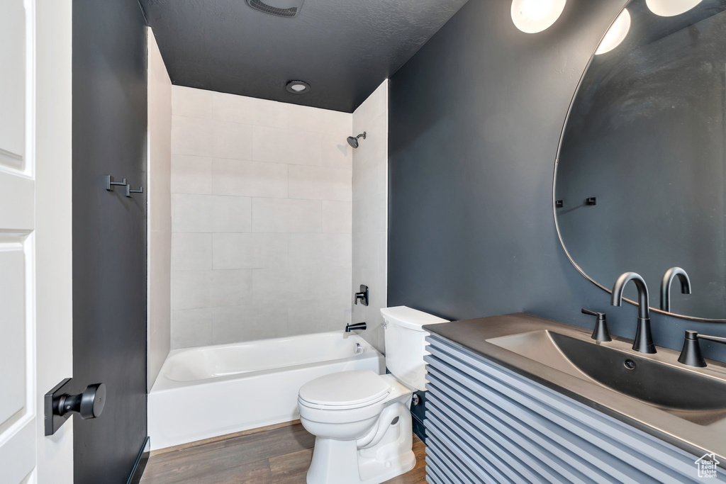 Bathroom with toilet, wood finished floors, shower / washtub combination, and vanity