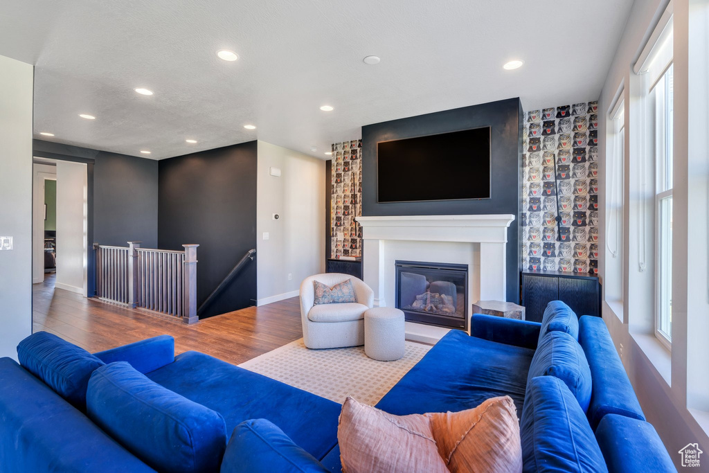 Living room featuring wood finished floors, recessed lighting, baseboards, and a glass covered fireplace