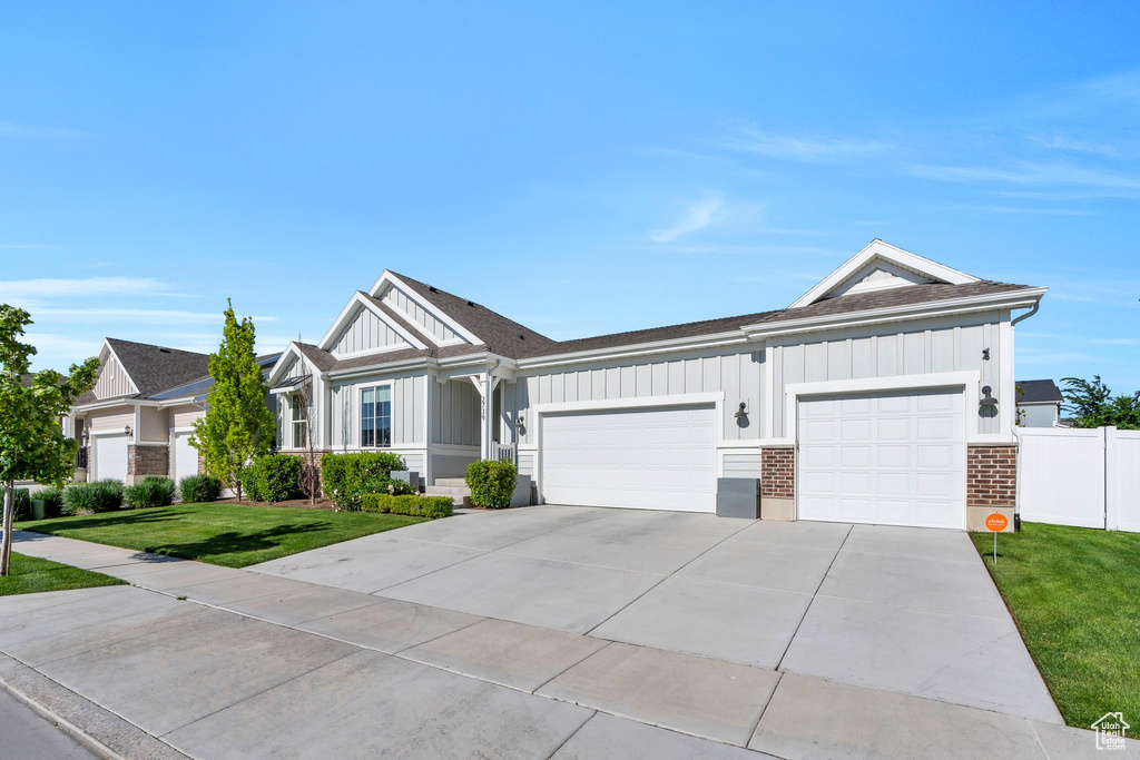 Ranch-style home with board and batten siding, an attached garage, concrete driveway, brick siding, and a shingled roof