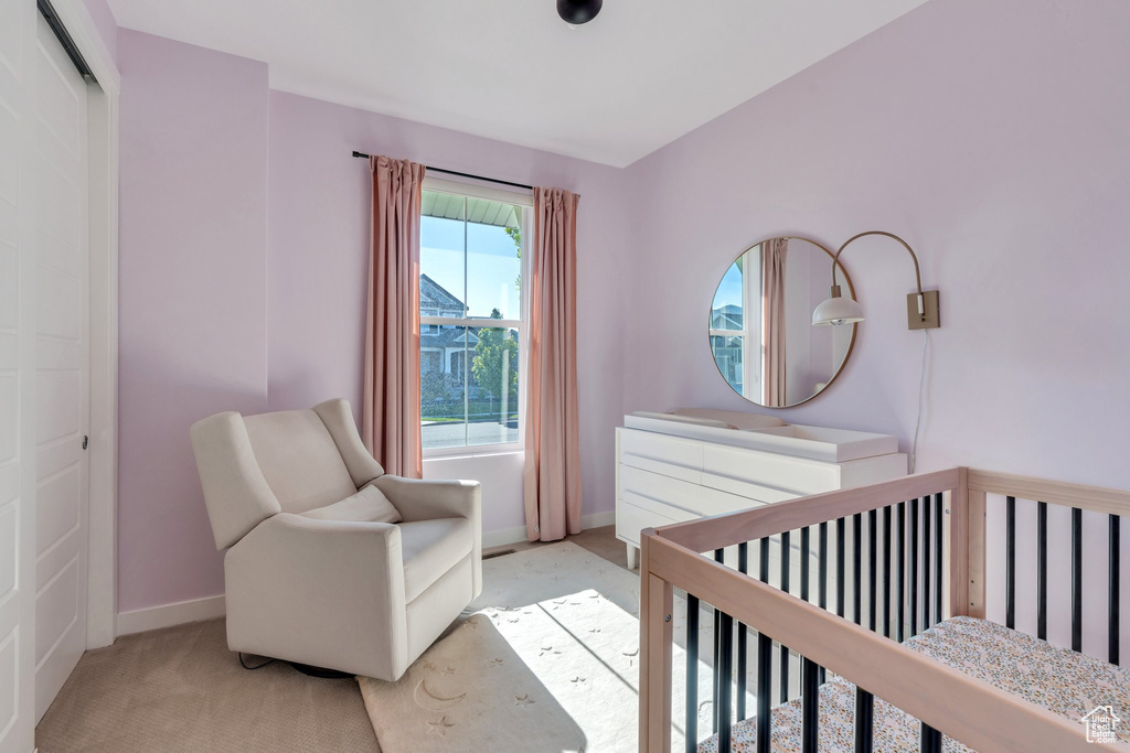 Bedroom featuring light carpet, baseboards, and a crib