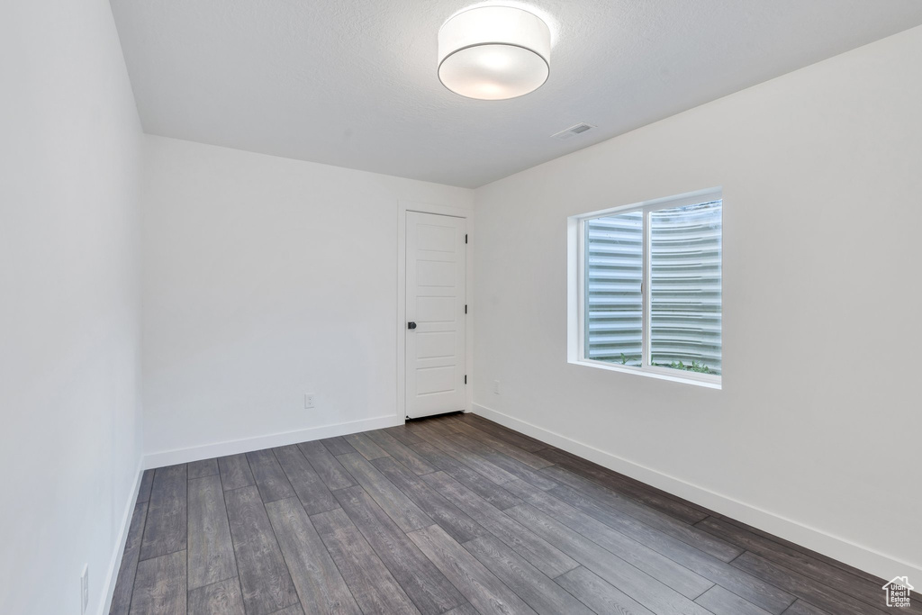 Unfurnished room featuring dark wood-style flooring and baseboards