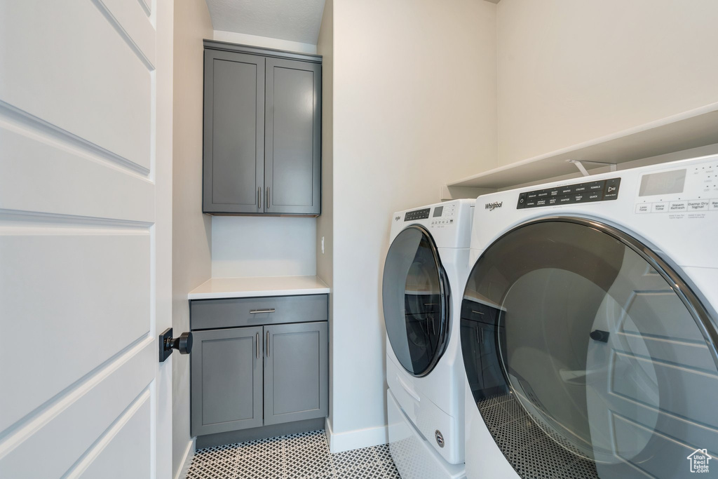 Washroom featuring washer and dryer, cabinet space, and baseboards