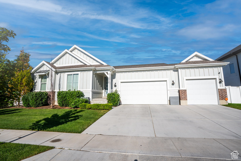 Ranch-style home featuring board and batten siding, a garage, a front yard, and concrete driveway