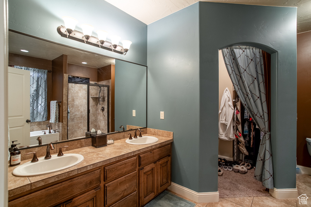 Bathroom featuring a stall shower, double vanity, tile patterned flooring, and a garden tub