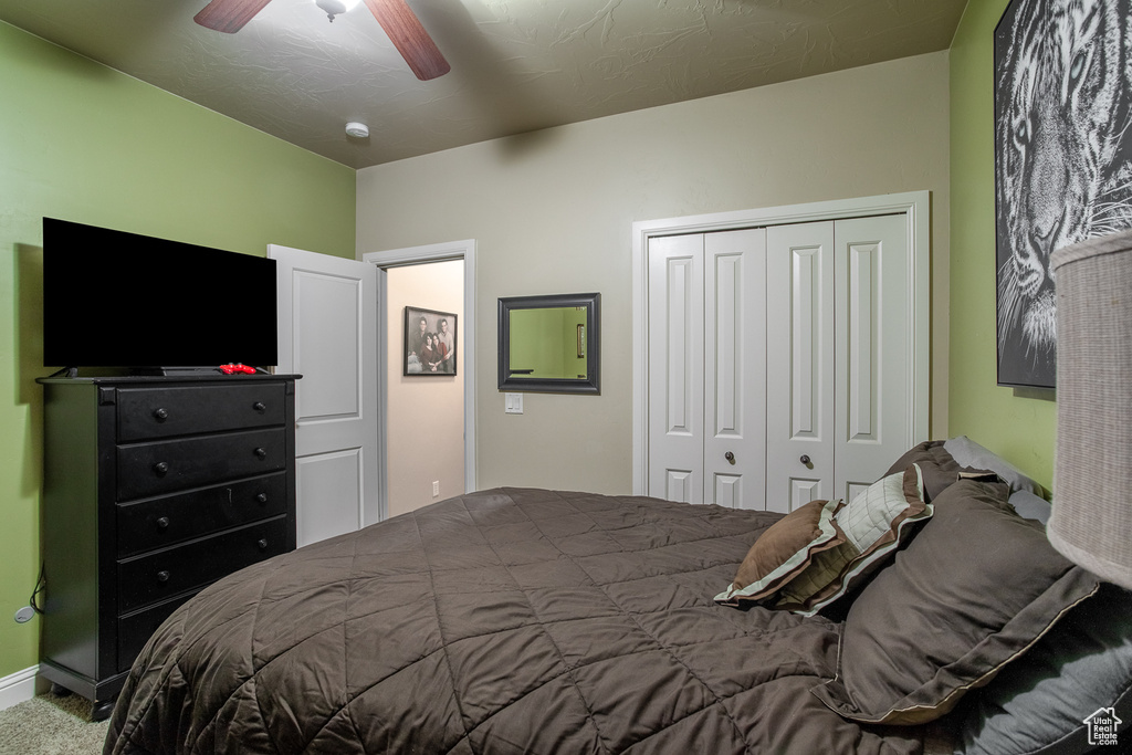 Carpeted bedroom with a closet and ceiling fan