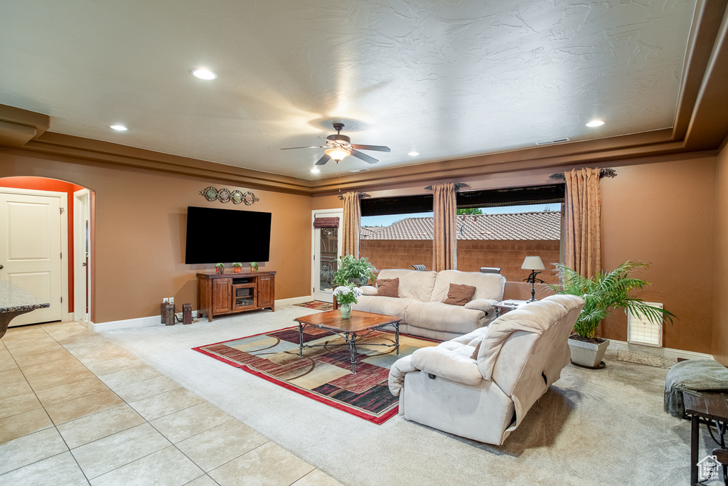 Carpeted living room with arched walkways, a ceiling fan, recessed lighting, and tile patterned flooring