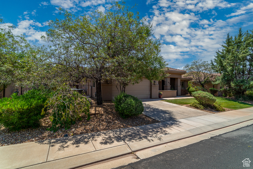 View of front facade featuring driveway, an attached garage, a tiled roof, and stucco siding