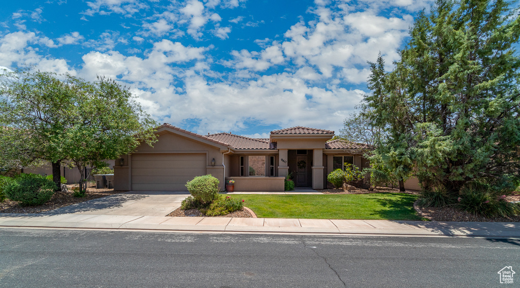 Mediterranean / spanish home featuring a garage, a tiled roof, driveway, stucco siding, and a front lawn