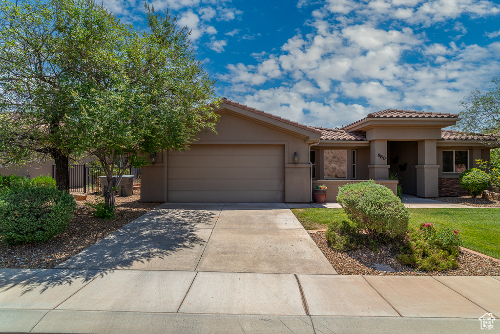 View of front facade with a garage, a tiled roof, stucco siding, and driveway
